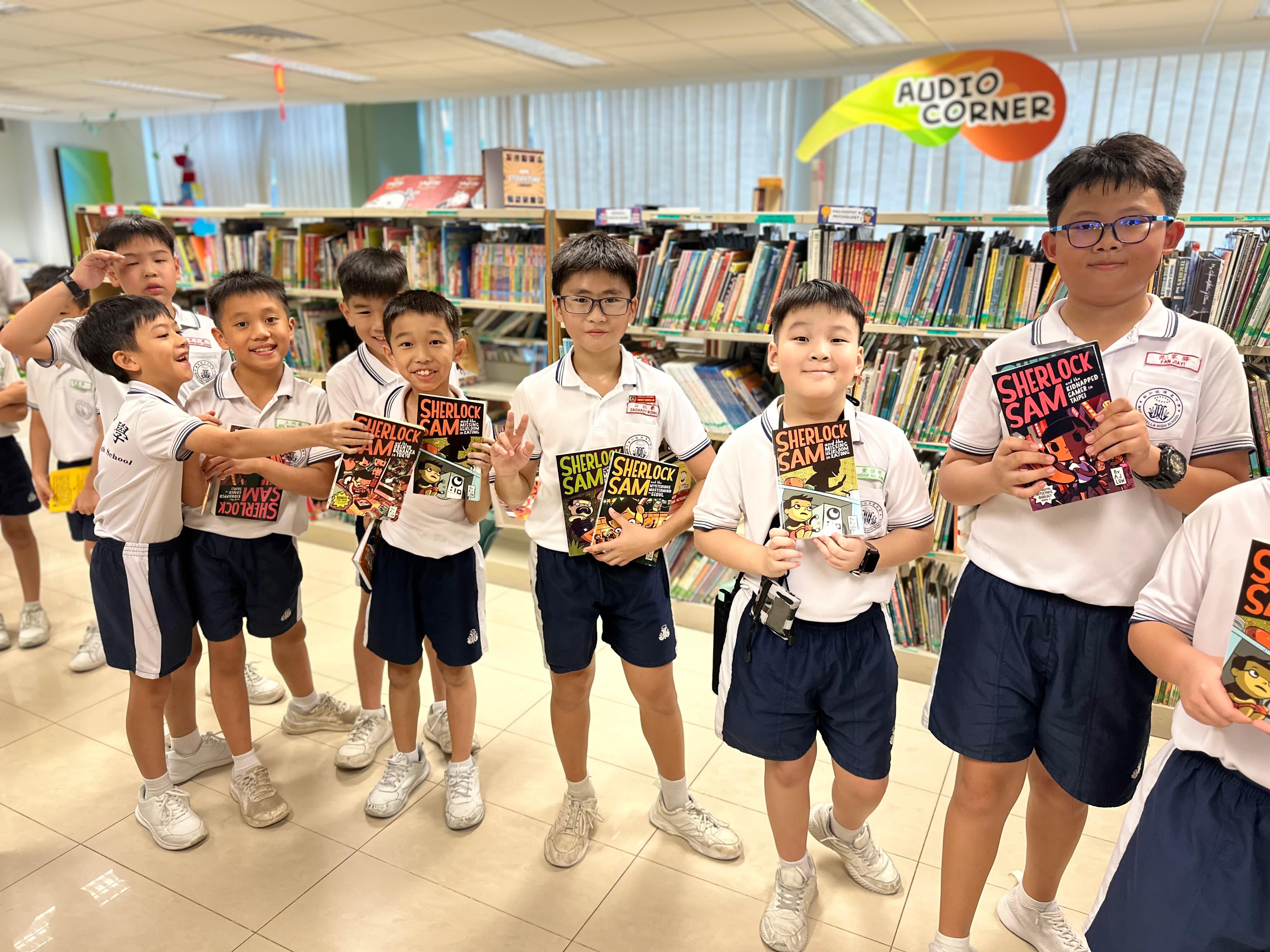 Young boys in white uniforms smile and interact in a colorful classroom with green leaf decorations.
